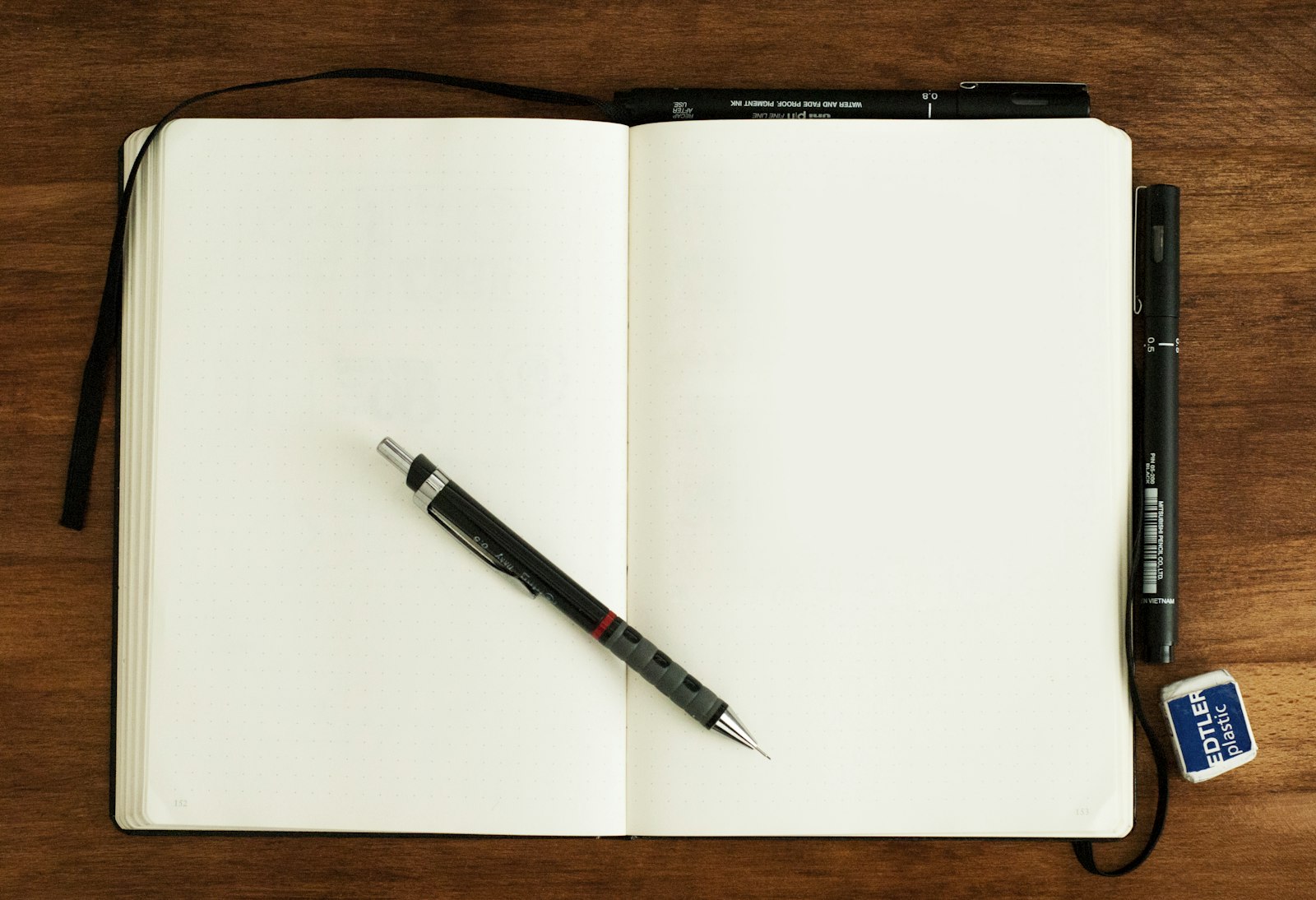 An open notebook with a pencil lying across it