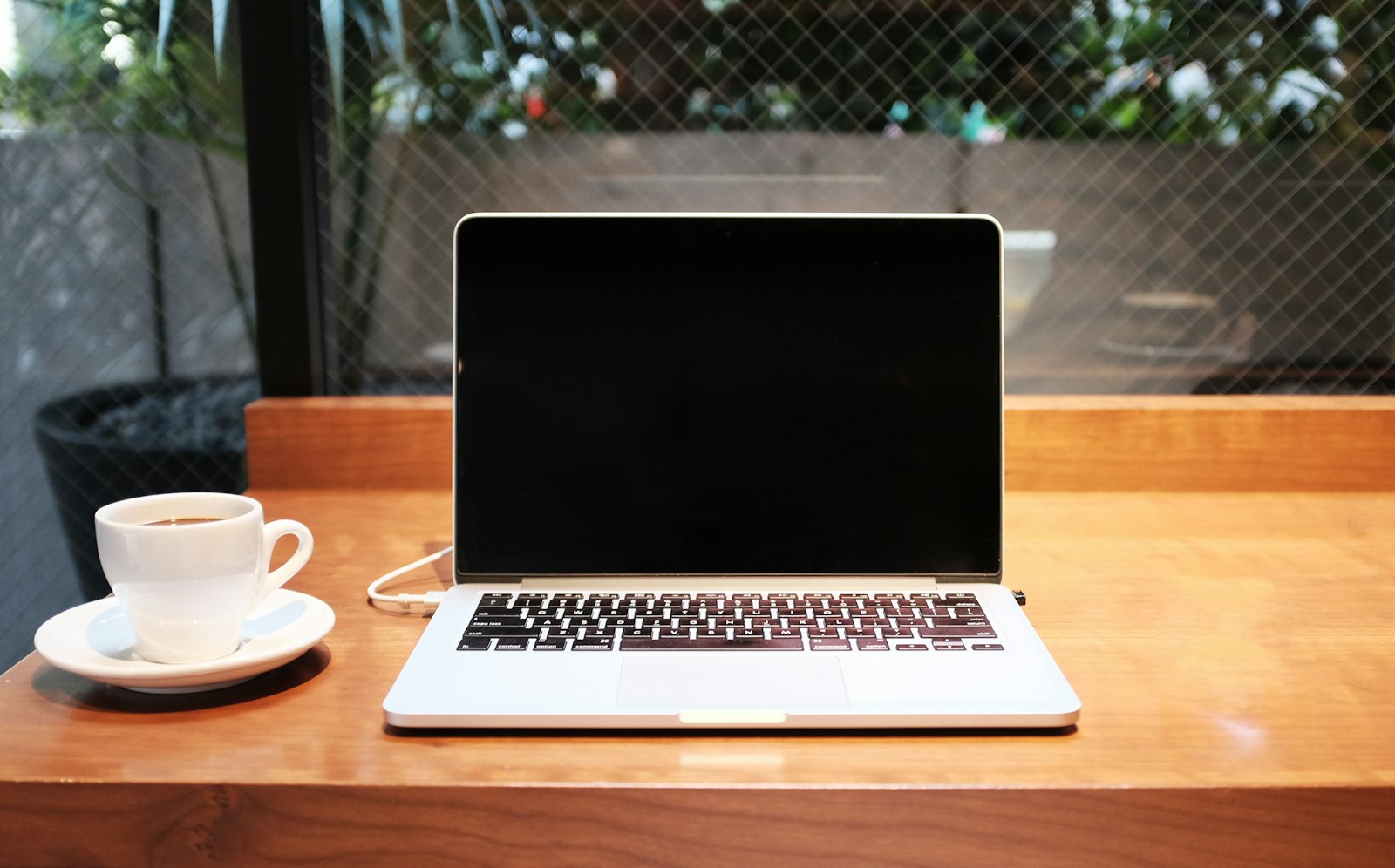 A laptop and a cup of coffee on a wooden café table