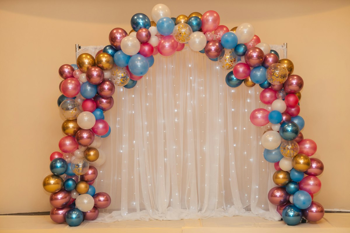 A colourful balloon arrangement against a white curtain