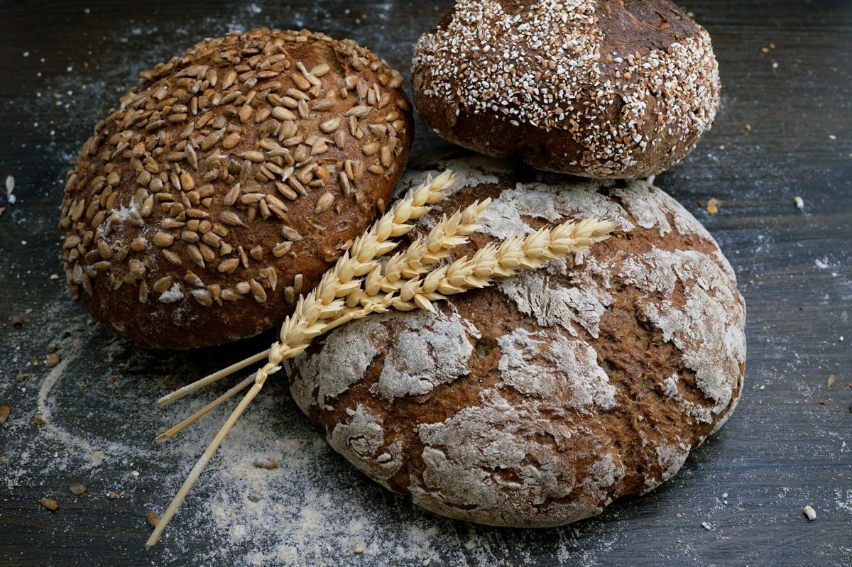 Three rustic loaves with seeds on a wooden board
